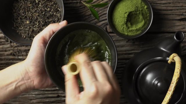 Preparing Japanese organic matcha green tea powder in the black bowl with wire whisk on wooden table, Organic product from the nature for healthy with traditional style
