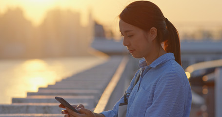 Woman use of smart phone under sunset in Hong Kong