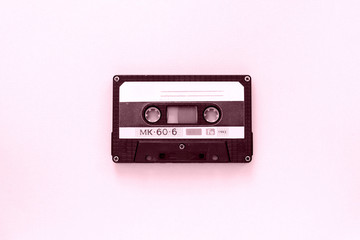 Old audio tape cassette close-up. Old technology concept. Pink color toned