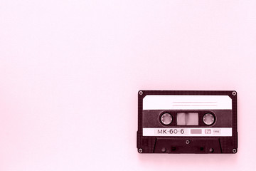 Old audio tape cassette close-up. Old technology concept. Pink color toned
