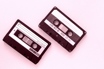 Obraz premium Two old audio tape cassettes close-up. Old technology concept. Pink color toned