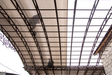 A worker mounts a metal canopy in the courtyard of the house