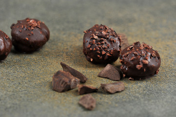 Handmade chocolates and pieces of dark chocolate on a dark surface.  Close-up.  Macro shot.