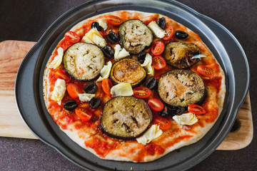 pizza base with tomato sauce veggies and aubergine before going in the oven