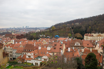 Fototapeta premium Panorama of the Czech city of Prague with tiled orange roofs from the observation deck of Prague Castle on a cloudy day on the eve of Christmas.
