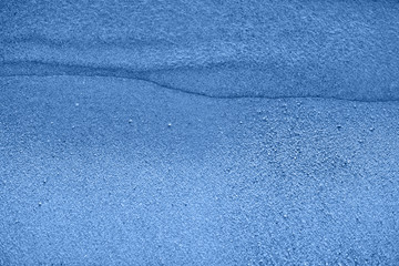 Sea wave and sand seashore in blue colored tone. Sunlight over the sea ocean waves. MIrror reflection on water surface. Macro close up.