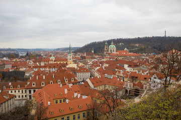 Fototapeta na wymiar Panorama of the Czech city of Prague with tiled orange roofs from the observation deck of Prague Castle on a cloudy day on the eve of Christmas.