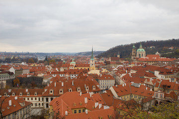 Fototapeta na wymiar Panorama of the Czech city of Prague with tiled orange roofs from the observation deck of Prague Castle on a cloudy day on the eve of Christmas.