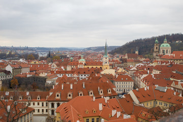 Obraz premium Panorama of the Czech city of Prague with tiled orange roofs from the observation deck of Prague Castle on a cloudy day on the eve of Christmas.