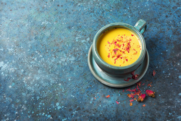 Healthy drink of golden turmeric milk with dry roses