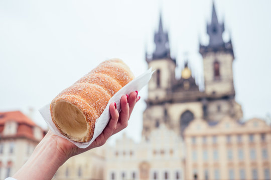 woman with an appetite eats a traditional Czech sweet Trdelnik in Prague street
