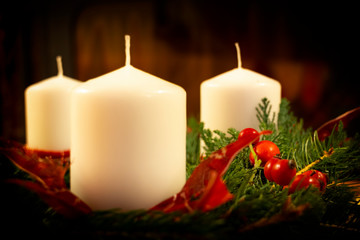 Christmas Wreath on the dark background. Christmas Wreath close-up. Candle, Spruce branches and rosehip berries.