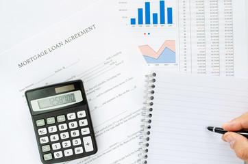 Calculating the payments on a mortgage loan in a conceptual image with calculator, notepad, pen and spreadsheets