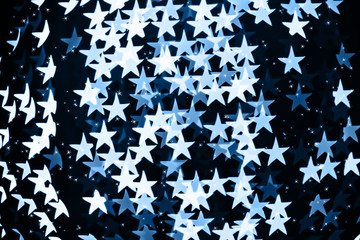 Star shaped holiday blurred blue bokeh background. Christmas background with sparkles. Celebration background. Horizontal.