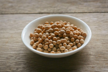 Soybeans in a white plate on wooden background. 