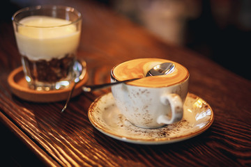 Cup of coffee on a wooden table. Copy space. Spoon on the froth with coffee that does not sink