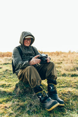 Old man taking photo in misty woods.