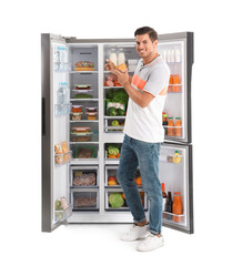 Man near open refrigerator on white background