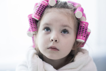 portrait of emotional little pretty girl with hair curlers