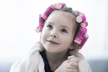 portrait of emotional little pretty girl with hair curlers