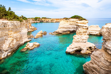 Torre Sant Andrea beach with its soft calcareous rocks and cliffs, sea stacks, small coves and the jagged coast landscape. Crystal clear water shape white stone create natural stacks. Melendugno Italy
