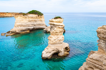 Torre Sant Andrea beach with its soft calcareous rocks and cliffs, sea stacks, small coves and the jagged coast landscape. Crystal clear water shape white stone create natural stacks. Melendugno Italy