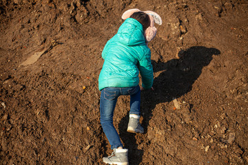 A girl is climbing a mountain. The child is dirty clothes.