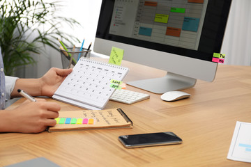Fototapeta na wymiar Woman making schedule using calendar at table in office, closeup