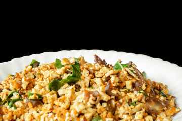 Closeup fusion vegan food in Thai northern style (Larp) in white ceramic plate isolate on black background. Thai and Chinese people popular eaten vegan foods in Chinese vegetarian festival.