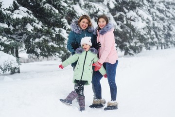 family-mother and two daughters having fun on the background of snow and forest. Winter entertainment