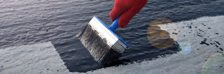Worker applies bitumen mastic on the foundation