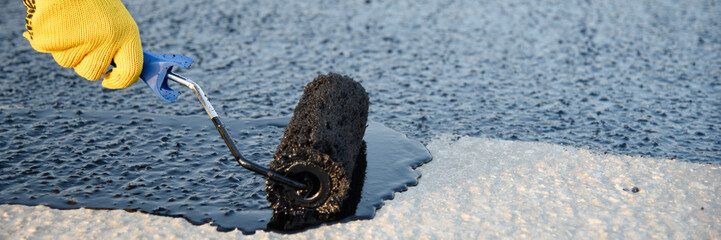 Worker applies bitumen mastic on the foundation