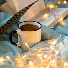 Coffee cup and garland on a bed. Atmospheric hygge style. Cozy winter or autumn concept