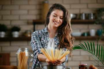 Young woman in kitchen. Beautiful woman making pasta. Cooking delicious dinner.