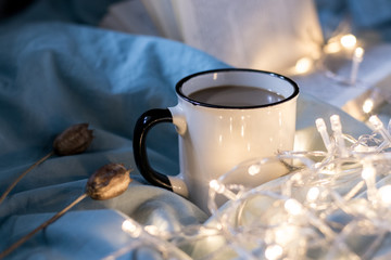 Coffee cup and garland on a bed. Atmospheric hygge style. Cozy winter or autumn concept