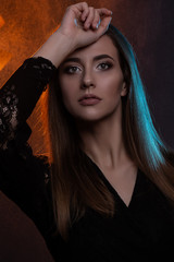 Obraz premium Close up beauty portrait of young beautiful woman in color backlight dressed in black. Studio shot.