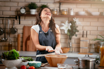 Young woman in kitchen. Beautiful woman having fun while making  dough.