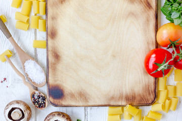 Kitchen board surrounded by vegetables and spices.
