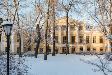 Fabulous snowy urban landscape. Ground and trees cover with fresh snow. On the background yellow palace. Winter season concept. Blue sky and sunlight.