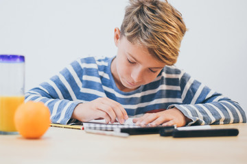 Naklejka premium Student drawing with pencil on the notebook. Boy doing homework writing on a paper. Kid hold a pencil and draw a manga at home. Teen drawing sitting at the table. Education art talent ability concept.