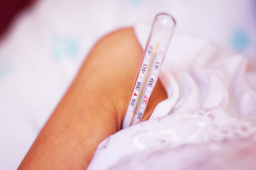 lying sick woman with thermometer in the armpit . Woman measures body temperature under his arm...