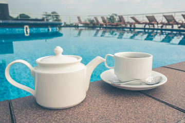 cup on the table near the pool . White ceramic coffee cup
