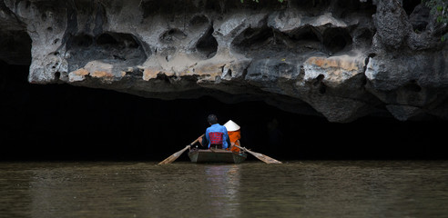 Rowing boat on river going under Limestone Karst, Ninh Binh, Vietnam © Paul