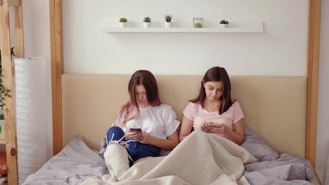 Teens phubbing. Modern social relationship. Female friends ignoring each other using smartphones.