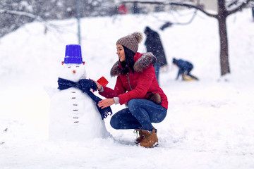 Fototapeta na wymiar snowman.Wintertime. Happy holiday. girl playing with snow on winter day.