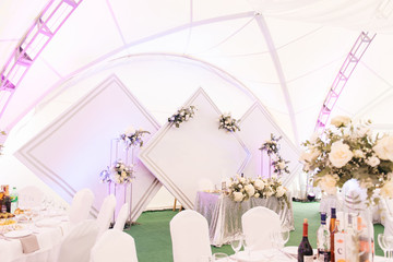 Decor concept for wedding and holiday, beautiful white tent decorated with flowers for the holiday, Presidium with diamonds of the bride and groom