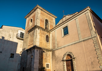 Fototapeta na wymiar The Church of Santa Chiara, built in 1275, in the historic center of Isernia, Molise, Italy. The bell tower, the crucifix and the wooden portal with a round arch.
