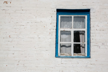 Window on a shabby white brick house wall.