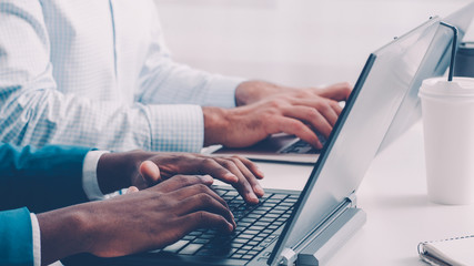 Corporate life. Office work routine. African business men working on laptops typing.