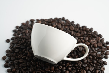 white cup on black coffee bean pile top view wite white background